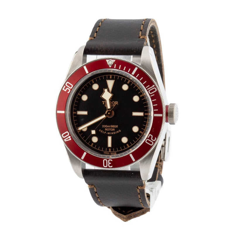 Tudor Heritage Black Bay 79220R avec lunette rouge et cadran noir, sur bracelet en cuir marron.