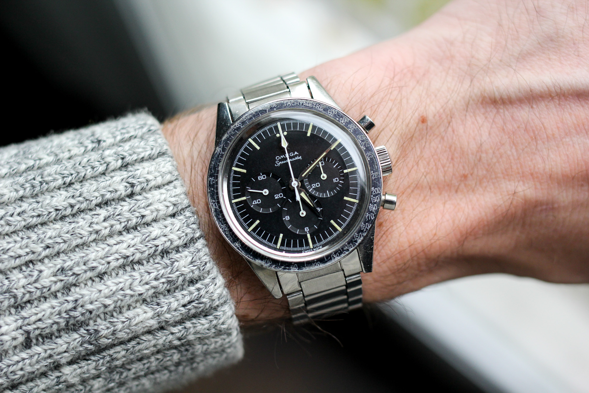 Omega Speedmaster vintage (ref. 2998-62) sur le poignet, montrant son cadran noir patiné, ses aiguilles alpha et son bracelet acier extensible d'époque